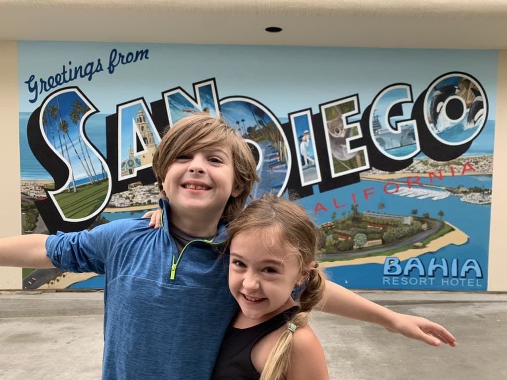 My kids Otis (8yo) and Emi (6yo) standing in front of a tourist mural that says San Diego