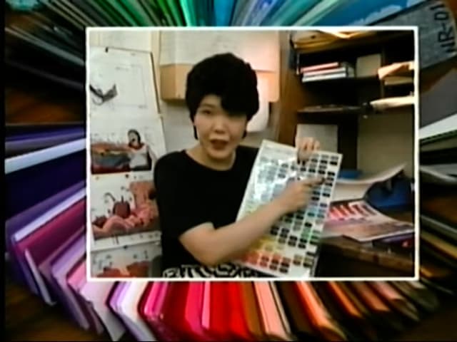 Kimie Yamada holding and pointing towards dark toned greys and blues on the color palette sheet