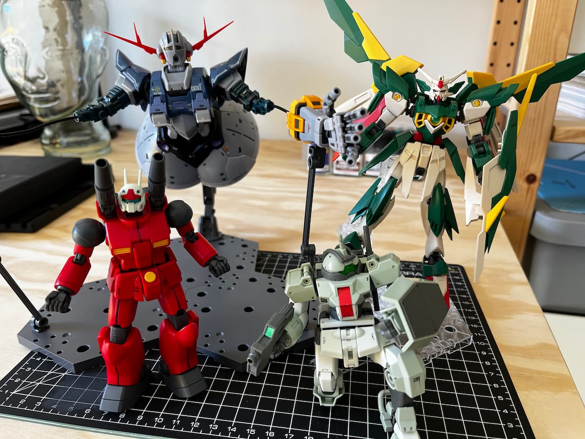 Four gunpla models: RG Zeong, HG Fenice, HG Demi Trainer, and HG Guncannon