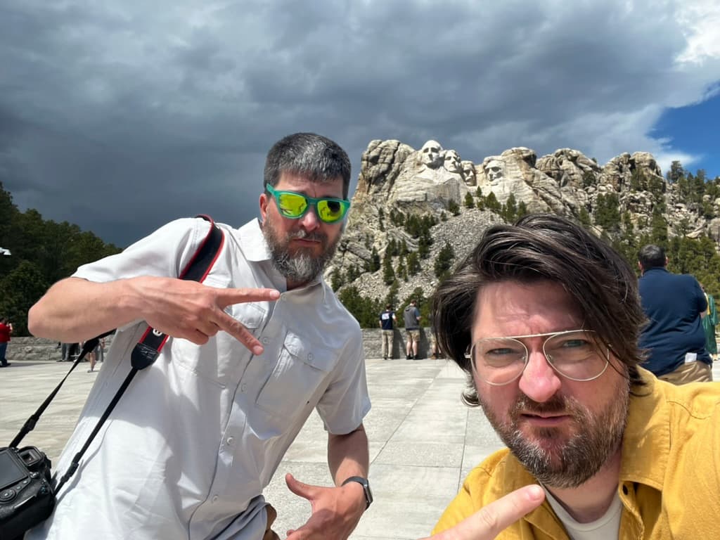 My brother and I giving a cool peace sign in front of Mount Rushmore on a cloudy day