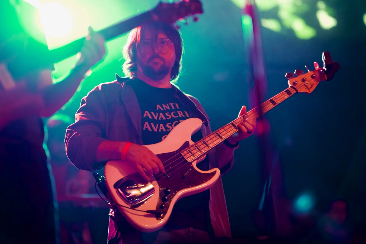 Me playing bass guitar drowned in moody green and purple rock show lighting